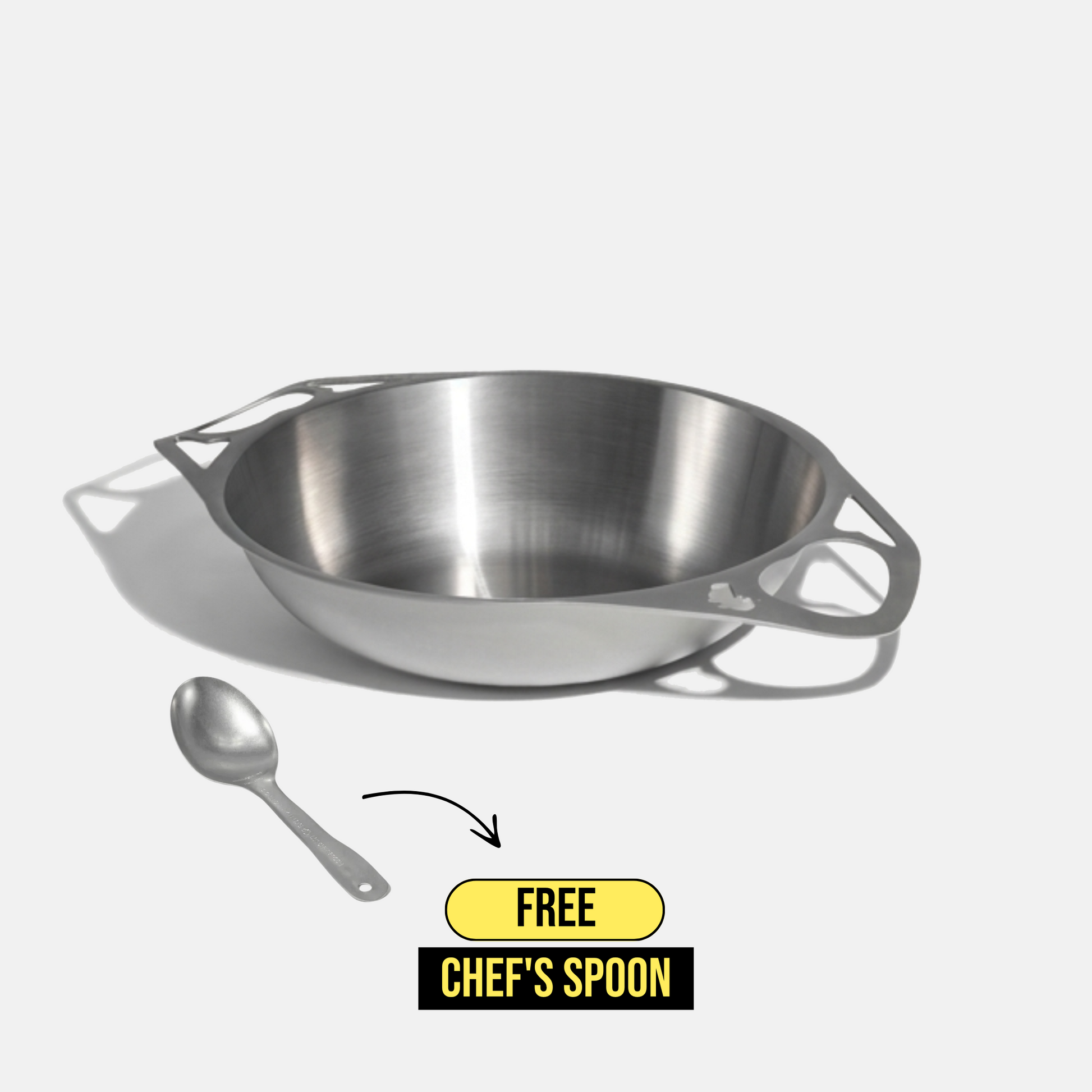 A stainless steel bowl with integrated side handles is shown on a light gray background, with a small chef's spoon below it and a yellow-and-black promotional badge reading 'FREE CHEF'S SPOON'.