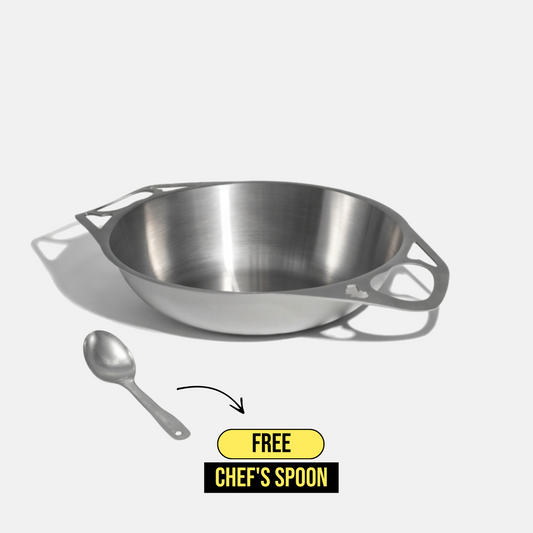 A stainless steel bowl with integrated side handles is shown on a light gray background, with a small chef's spoon below it and a yellow-and-black promotional badge reading 'FREE CHEF'S SPOON'.